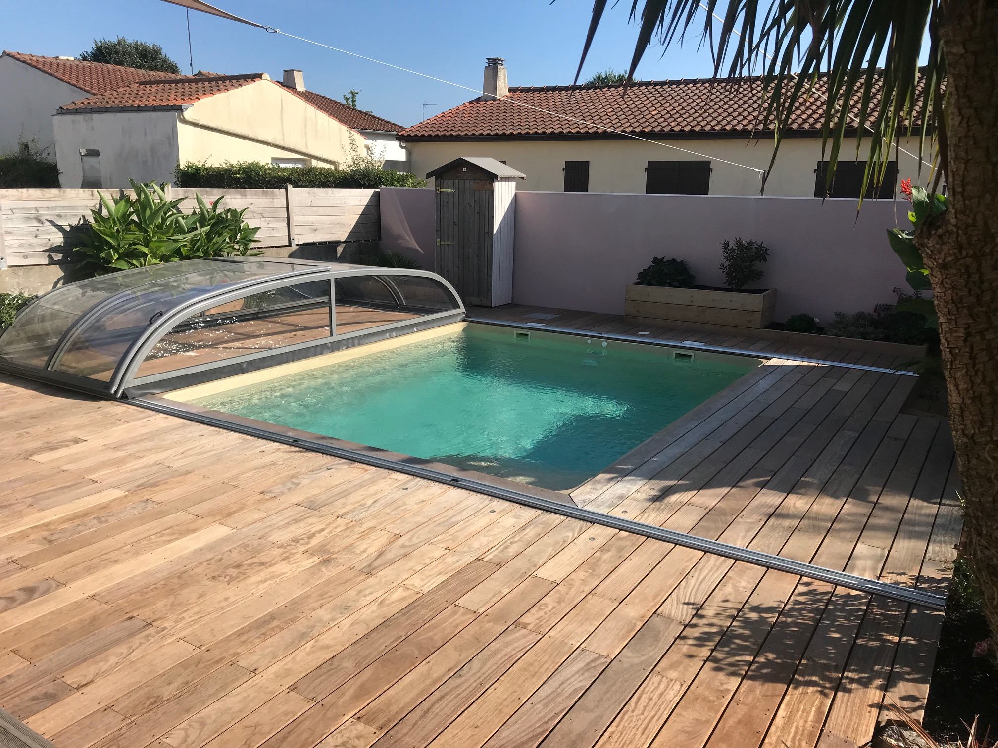 Piscine avec abri mi-haut, et lame de bois au sol - Piscines Excellence
